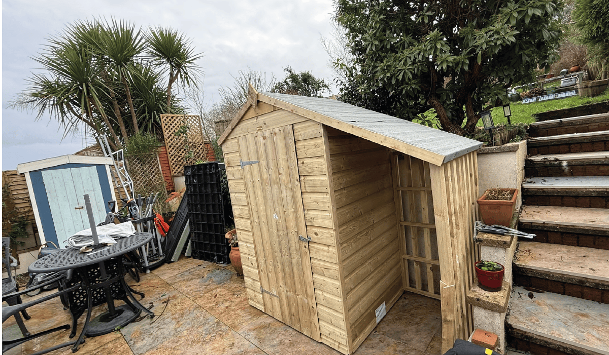 a shed with log store assembled on a patio